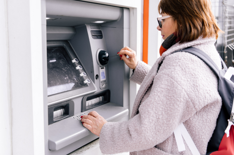 Employee withdrawing funds using Payhawk corporate card at an ATM